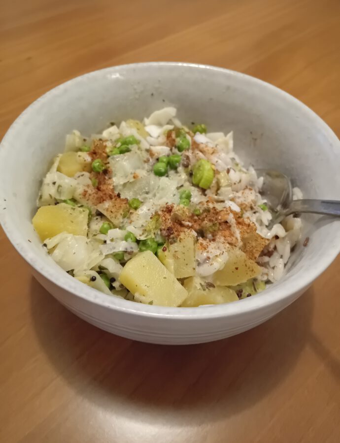 Kruidige Indiase curry met witte kool, aardappels, prei en erwten geserveerd met orzo